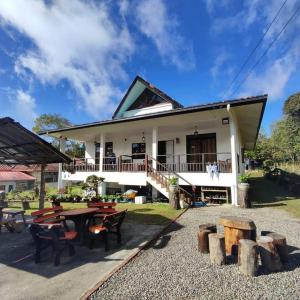 a house with picnic tables in front of it at Bonsai Villa @ Mesilou 盆栽小苑 in Kampong Kundassan