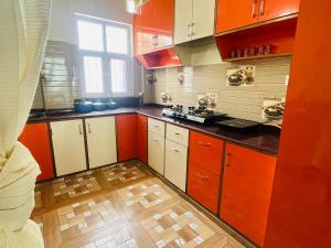eine Küche mit orangefarbenen und weißen Schränken und Holzböden in der Unterkunft HILLS HOME in Shimla