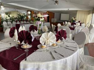 una sala banchetti con tavoli e sedie bianchi con fiori rossi e bianchi di NEW HOTEL CRUZ DEL SUR a Concepción