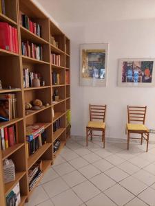 ein Zimmer mit 2 Stühlen und Bücherregalen mit Büchern in der Unterkunft Casa Marina Taormina in Taormina