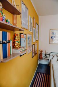 a room with a yellow wall with shelves and books at sleepArt room for 2 in Celle
