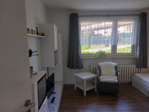 a small room with a television and a chair and a window at Pension am Sonnenhof in Schmalkalden