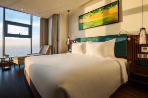 A bed or beds in a room at Maximilan Danang Beach Hotel