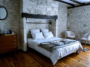 Les chambres du Roc في Le Roc: غرفة نوم بسرير وجدار حجري