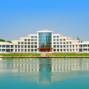 a large white building next to a body of water at Agsaray Deluxe Hotel & SPA in Mingachevir