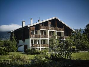 a large wooden house with a balcony and trees at La Maison Les Peupliers in Courchevel