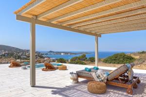 a patio with a pergola and chairs and the ocean at Syros Grace eco-Villa with Jacuzzi & Stuning Views in Ano Syros