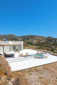a group of chairs sitting on a patio with a building at Syros Grace eco-Villa with Jacuzzi & Stuning Views in Ano Syros