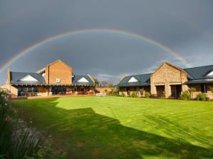 a rainbow over a house with a green lawn at 2 Owls Guesthouse in Potchefstroom