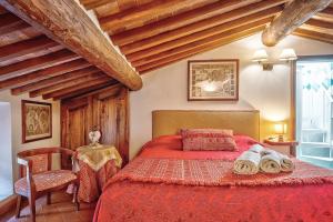 a bedroom with a red bed and a chair at Renaissance Apartment in Pienza