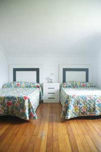 um quarto com 2 camas e piso em madeira em Casa da Castañuela em Muros