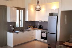 a kitchen with white cabinets and a refrigerator at Antel's Leisure Beach House Pelion in Volos