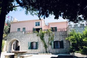 a large pink building with a stone wall at Villa Conte in Panayías