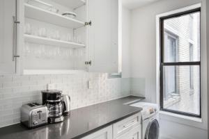 a white kitchen with a counter top with a microwave at Midtown 2br w doorman wd nr Central Park NYC-1144 in New York