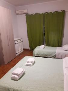 ローマにあるOlimpica Relais guest house CIR 28624の緑のカーテンとタオルが備わる客室内のベッド2台