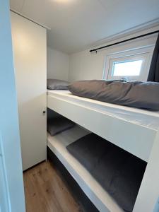 1 Schlafzimmer mit 2 Etagenbetten und einem Fenster in der Unterkunft Tiny House in de duinen van IJmuiden aan Zee in IJmuiden