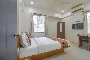 een witte slaapkamer met een bed en een raam bij FabHotel Skylight Studio Rooms in Pune