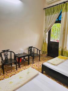 a room with three beds and a table and a window at Nhà Nghỉ Trường Lệ in Sầm Sơn