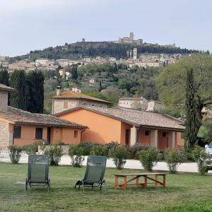 dos sillas y una mesa frente a un edificio en Giotto Country House & Spa en Assisi