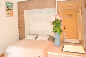 1 dormitorio con 1 cama y un jarrón con flores en Haliviera - Golden Square, 1min from beach, en Niza