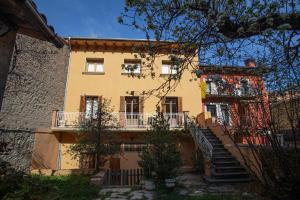 una casa amarilla con escaleras que conducen a ella en El Jardí de Can Prat, en Ripoll