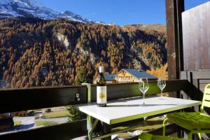 a table with wine glasses on a balcony with a mountain at Vue à couper le souffle Arellaz 42 in Zinal