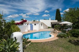 a villa with a swimming pool in front of a house at The Carobs Villas in Carvoeiro