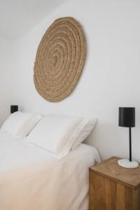 ein Schlafzimmer mit einem Bett und einem Rattanhut an der Wand in der Unterkunft The Carobs Villas in Carvoeiro