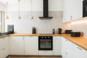 una cocina con armarios blancos y horno negro en The Carobs Villas, en Carvoeiro