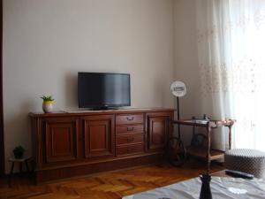 a living room with a flat screen tv on a wooden cabinet at Village Apartment 