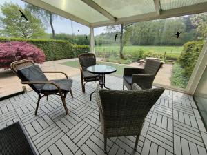een patio met stoelen en een tafel met uitzicht op een tuin bij Inviting bungalow in Gelderland with garden in Garderen