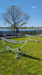 a couple of hammocks sitting on the grass near the water at Add Story Guest House in Rēzekne