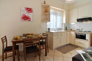 cocina con mesa de madera y sillas y cocina con fregadero en Ilios Studios, en Paleokastritsa