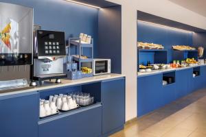 eine Bäckerei mit blauen Wänden und einer Theke mit Essen in der Unterkunft B&B HOTEL Madrid Aeropuerto T1 T2 T3 in Madrid