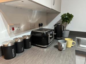 a kitchen counter with several trash cans and coffee mugs at 3 Bed Home Sleeps 6 - Long Stays - Contractors & Relocators with Parking, Garden & WiFi in Milton Keynes