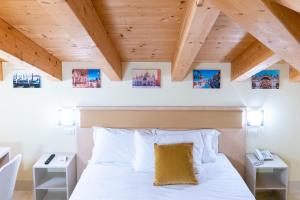 una camera da letto con letto, lenzuola bianche e soffitti in legno di Hotel Autoespresso Venice a Marghera