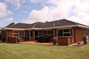 a brick house with a deck and lawn at House Located at the centre of East Auckland walking to Botany Westfield Shopping Mall in Auckland