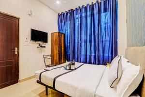 a bedroom with a bed with a blue curtain at Hotel Agoura Prime in Lucknow