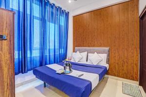 a room with a bed with blue sheets and a window at Hotel Agoura Prime in Lucknow