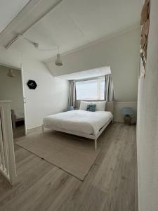 a white bedroom with a bed and a window at Voilà! - beach at 500m- free parking in Noordwijk aan Zee