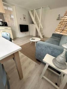 a living room with a blue couch and a kitchen at Voilà! - beach at 500m- free parking in Noordwijk aan Zee