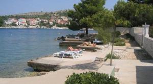 a group of people laying on a beach next to the water at Apartment in Zaboric with sea view, balcony, air conditioning 5178-3 in Šibenik