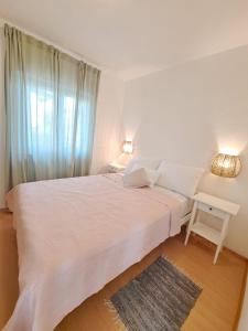 a bedroom with a large white bed with a window at Villa Porto in Rogač