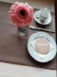 uma mesa com um prato e um vaso com uma flor em Alpenpension Maderer em Gaschurn