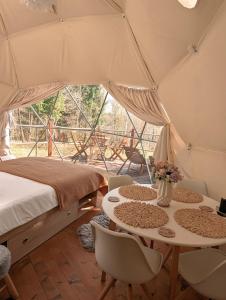 une tente avec un lit, une table et des chaises dans l'établissement Medve Dome - Luxury Camping in the middle of nature, à Vlăhiţa