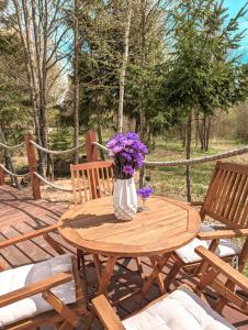 a wooden table with a vase of purple flowers on it at Medve Dome - Luxury Camping in the middle of nature in Vlăhiţa