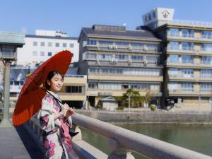 uma mulher de quimono segurando um guarda-chuva vermelho em Ohashikan em Matsue