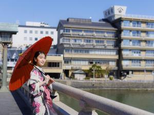 a woman in a kimono holding a red umbrella at Ohashikan in Matsue