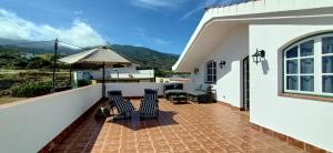 een patio met stoelen en een parasol op een huis bij Casa Abona, precioso ático con wifi gratis y vistas increíbles al mar y la montaña in La Sabinita