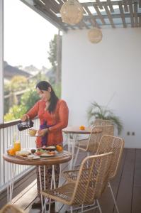 una donna che prepara il cibo su un tavolo sul balcone di The Bed by The Sea a Canggu